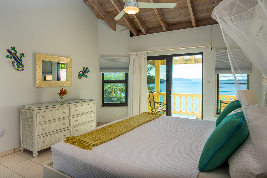 A Dream Come True Villa’s master bedroom with a king bed and sliding glass door leading to a private patio over Mahoe Bay.