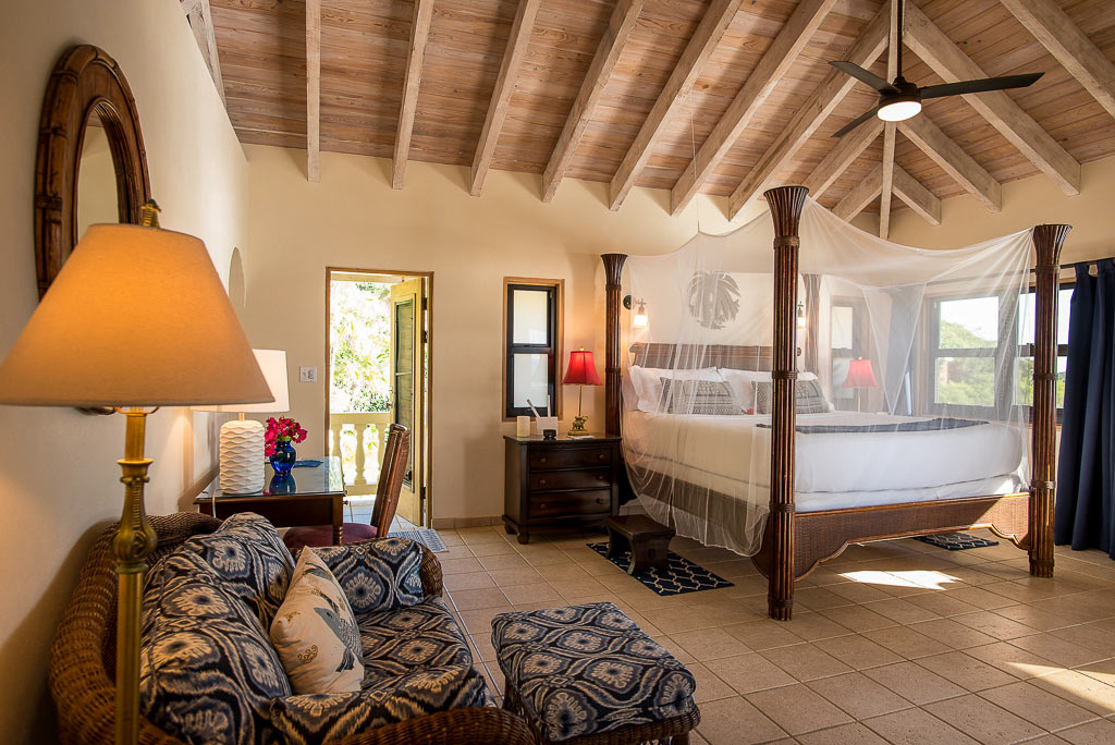 Master Bedroom at A Dream Come True Villa with a four-post king bed, lofted wood-beam ceilings and comfortable sitting area.