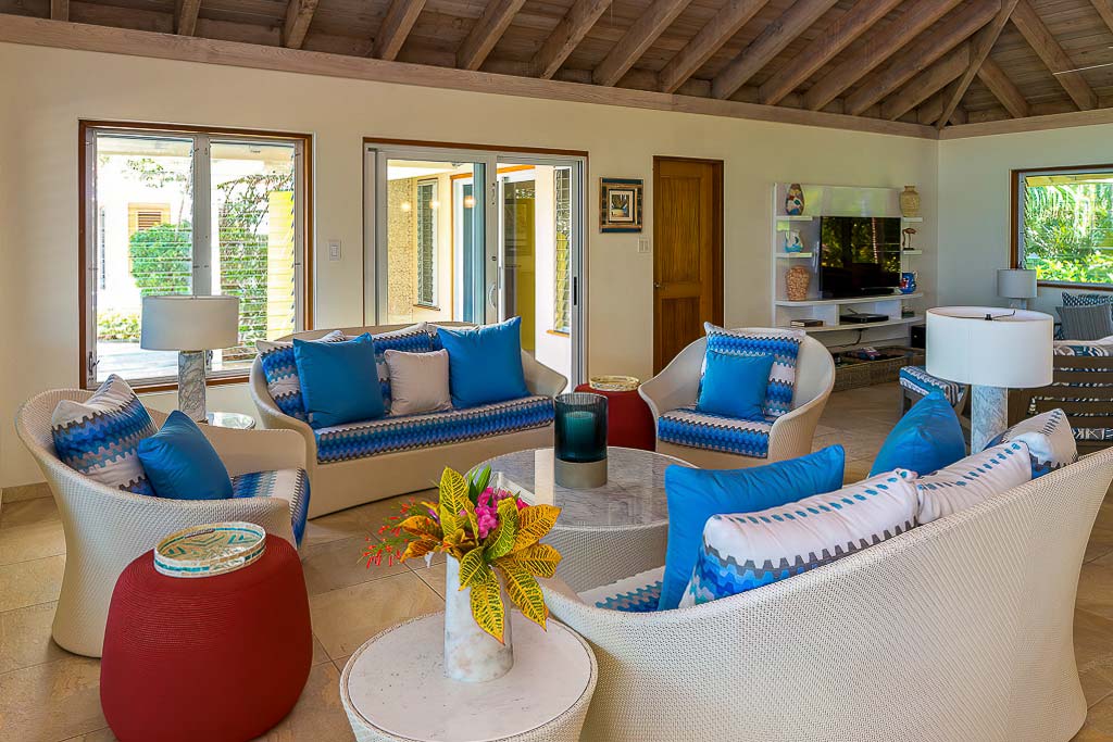 Living room area in the main room at Beachcomber Villa with comfortable couches and seats around a glass-top coffee table.