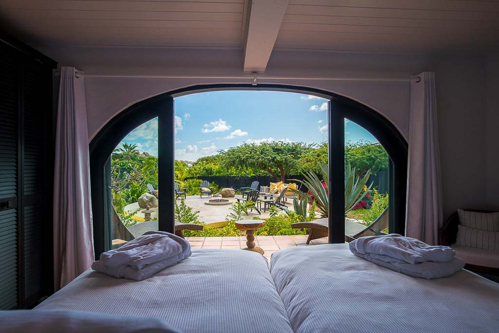 Cornucopia Villa’s twin-bed room with a charming arched glass doorway looking out to a patio and tropical gardens.