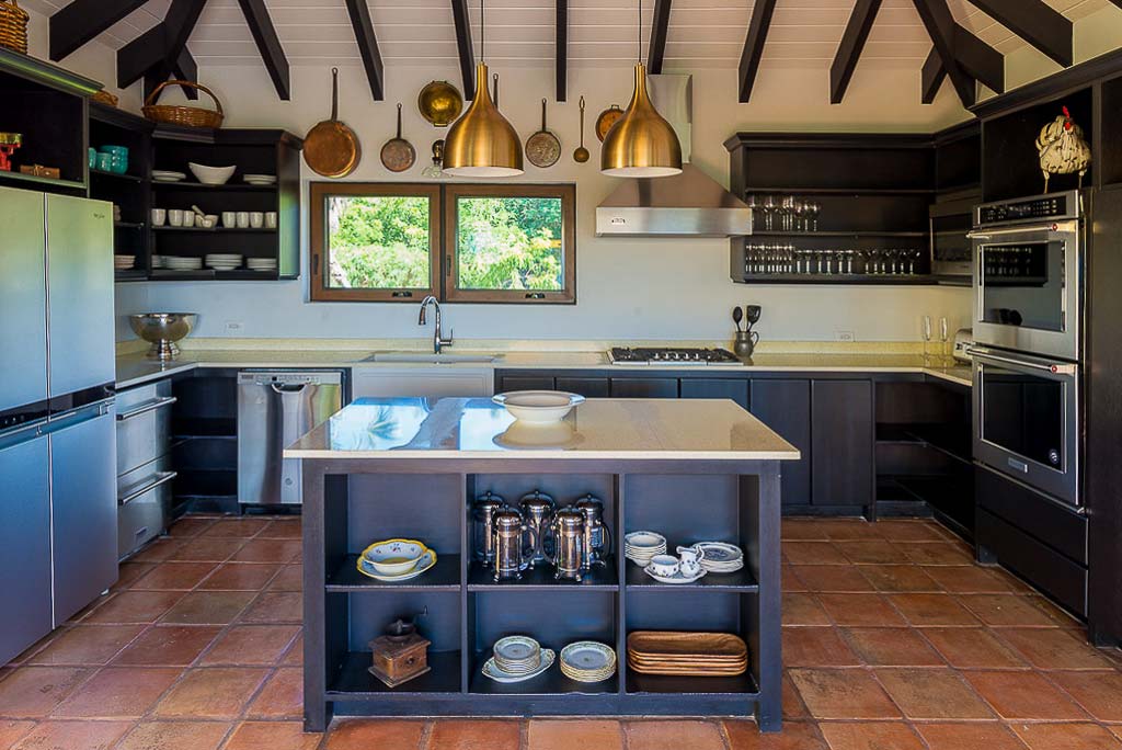 Cornucopia Villa’s chef’s kitchen with white countertops, steel appliances, a central island and lofted wood-beam ceiling.