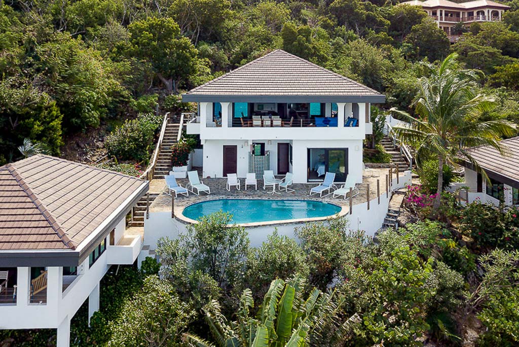 Dos Sols Villa’s elegant main house and adjacent cottage with a stone deck and fresh-water pool in the middle.