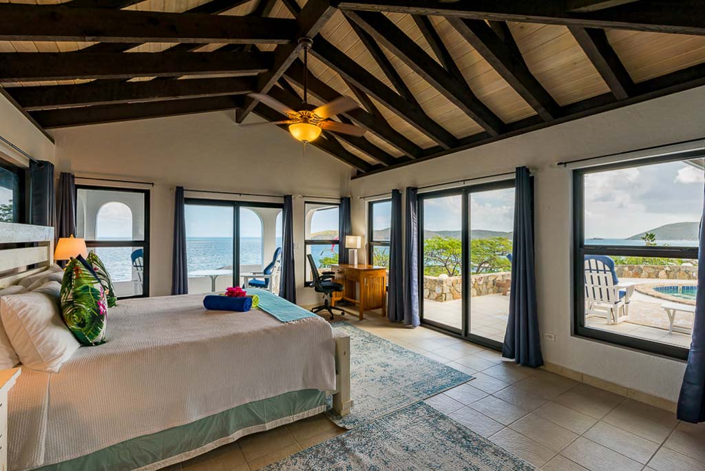 Euphoria’s spacious master bedroom with tile floors, lofted wood-beam ceilings and doors leading to the patio and pool.