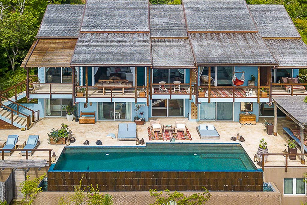 La Vida Villa’s two-level façade with multiple elevated balconies looking out on a large stone sundeck and pool.