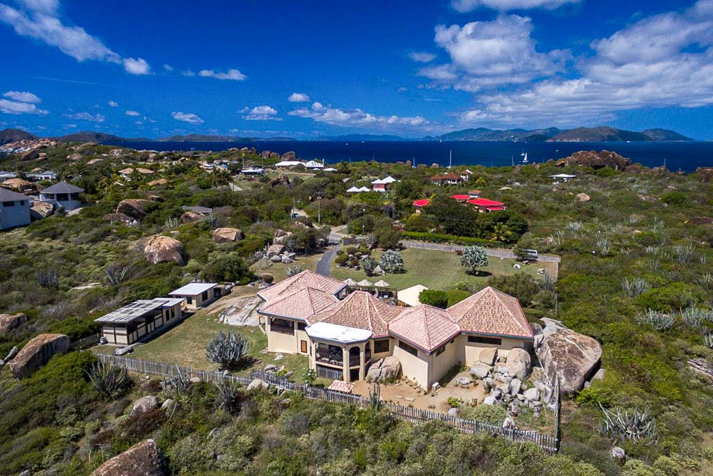 Multi-level, natural stone Mon Repos Villa exterior on a large square property with The Baths, Virgin Gorda in the background.
