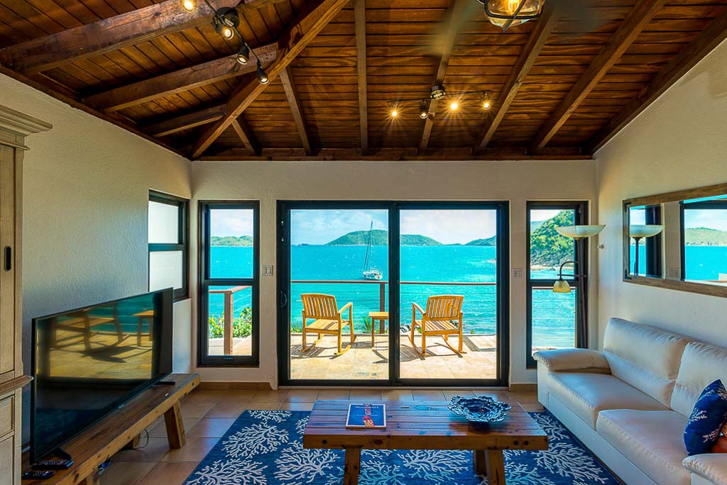 Separate living room with couch and flat-screen TV and large glass doors looking out on the blue waters of Leverick Bay.