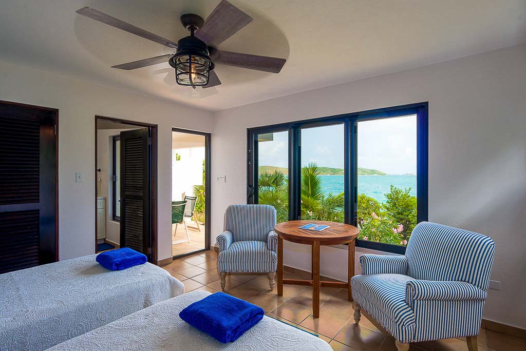 Rainbow’s End Villa double bedroom with twin beds and en-suite bathroom and door to a private, seaside patio on Leverick Bay.