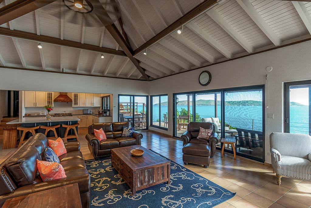Rainbow’s End Villa’s great room with an open kitchen and living area with large windows looking out on Leverick Bay.