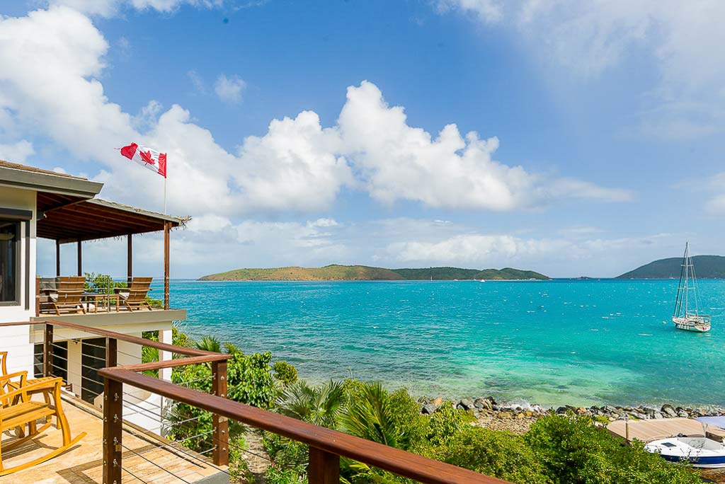 Rainbow’s End outdoor patio space right above the calm, crystal blue waters of Leverick Bay on a clear, sunny day.