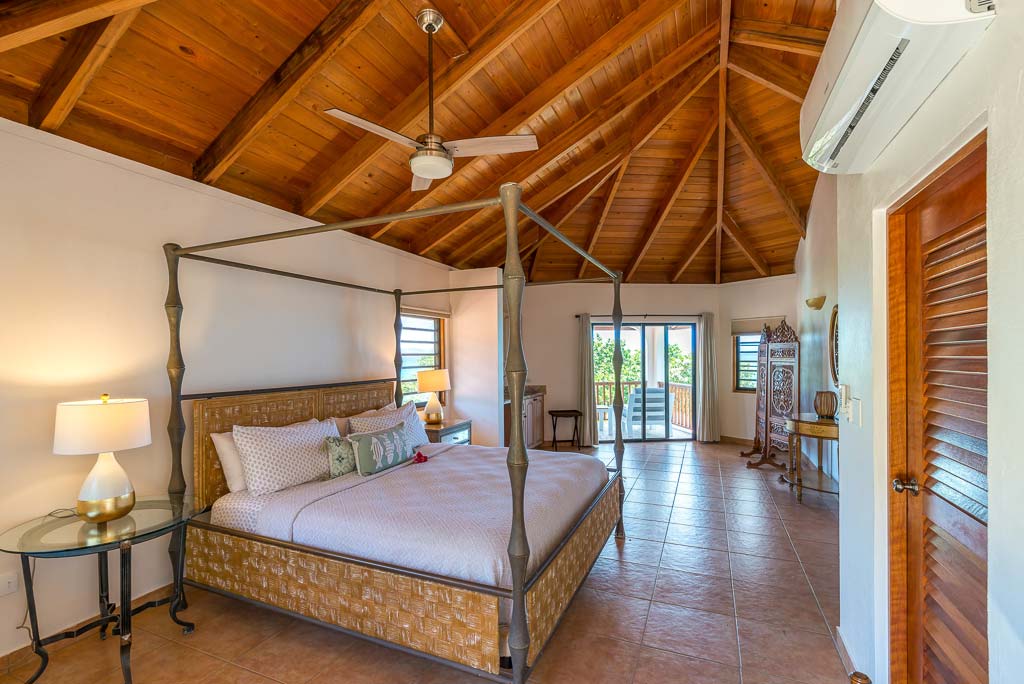 Sea Palms Villa guest room with two double beds, tile floors, wood ceiling with fans and glass door leading to a patio area.