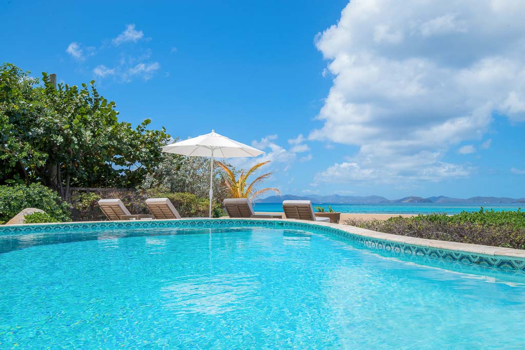 Oceanfront swimming pool at Sea Palms Villa with the blue waters of Mango Bay in the background on a sunny day.