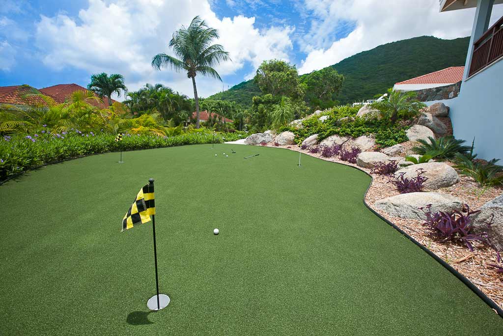 Practice putting green outside Blue Lagoon Villa surrounded by a tropical garden with a lush green hillside in the background.