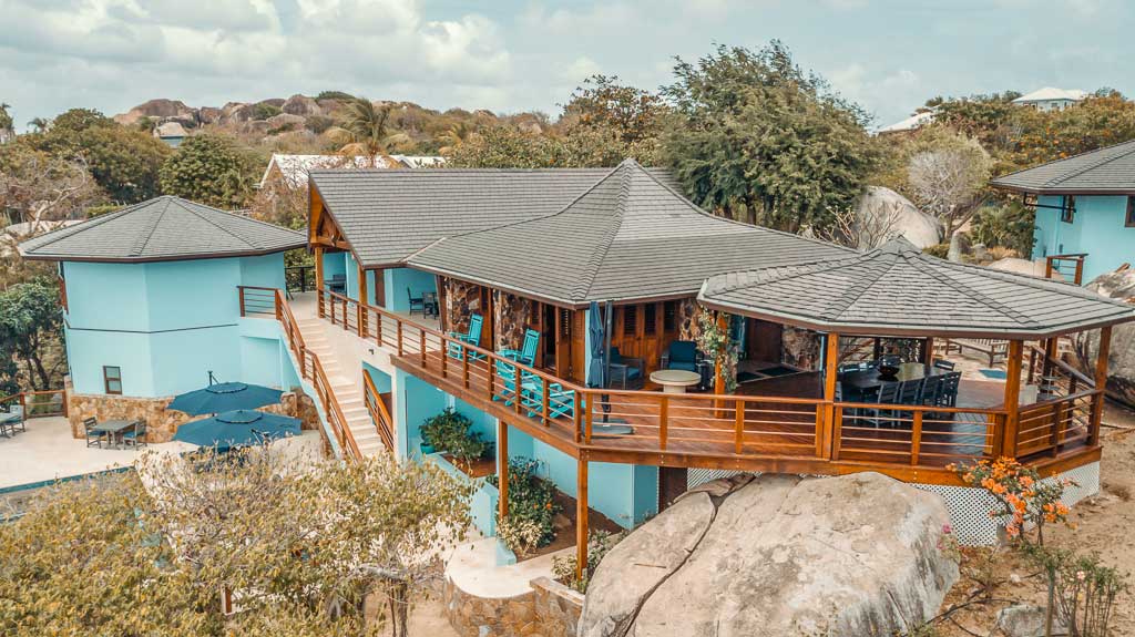 Eden Waters Villa in Little Trunk Bay surrounded by large boulders, trees and tropical flowers and vegetation.
