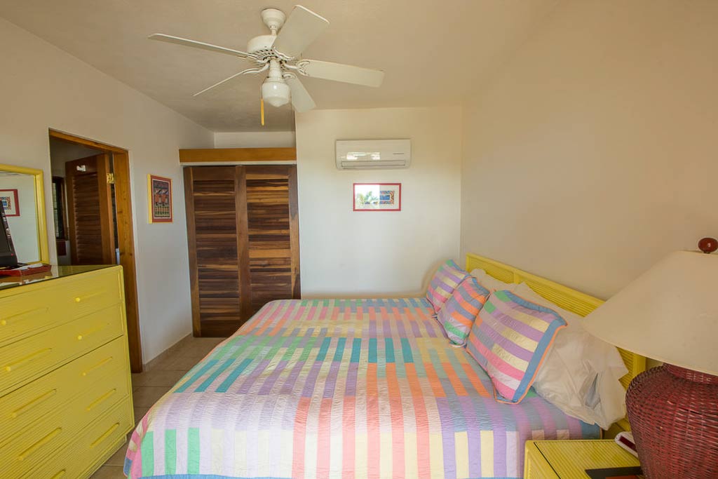 Loblolly guest room with a king bed, yellow bureau, white walls and ceiling and wood plank closet and bathroom doors.