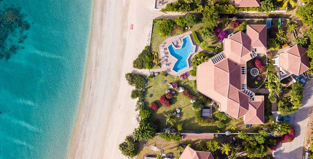 Overhead Sandcastle luxury villa with it’s red tile roof, manicured grounds and pool on the beach at Mahoe Bay.