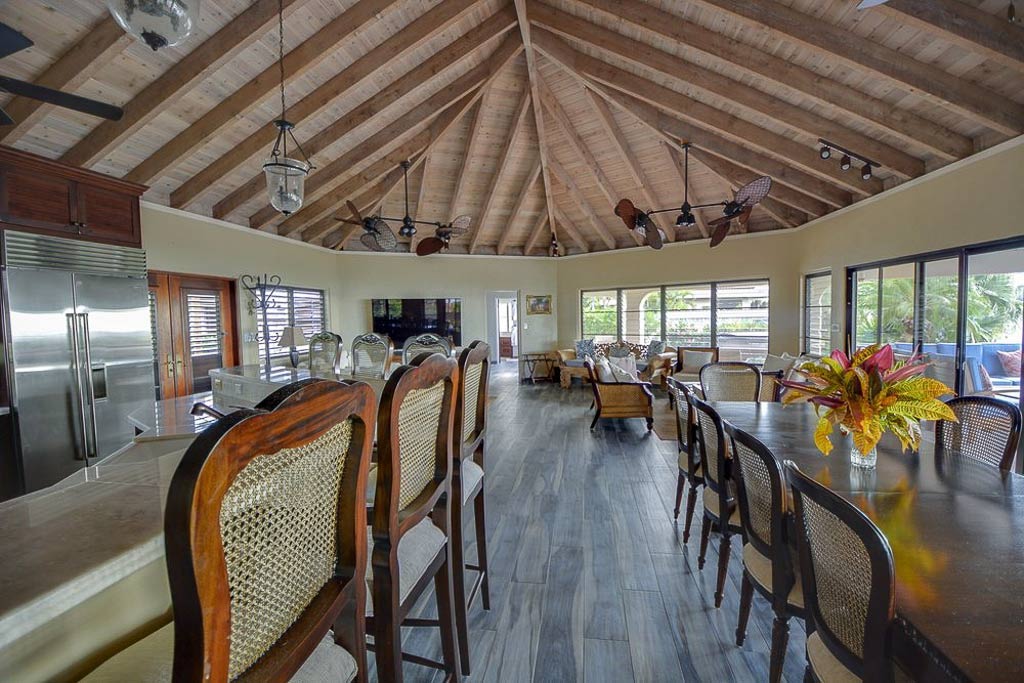 Kitchen bar and dining area in a bright and spacious main room at Sandcastle Villa with lofted wood-beam ceilings with fans.