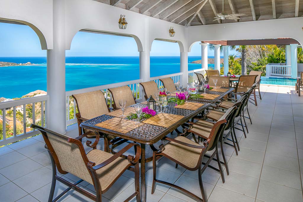 Formal outdoor dining area on Villa Tamar’s covered patio with the waters of Leverick Bay and the pool in the background.