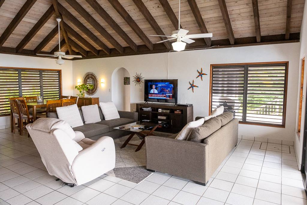 Villa ValMarc main room living area with ceiling fans, white tile floors, comfortable couches and chair and a flat-screen TV.