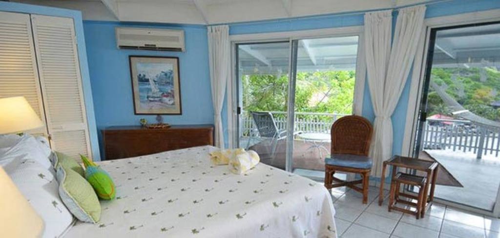 Vista Villa guest bedroom with a king bed, blue walls and sliding glass door to a private patio above Leverick Bay.