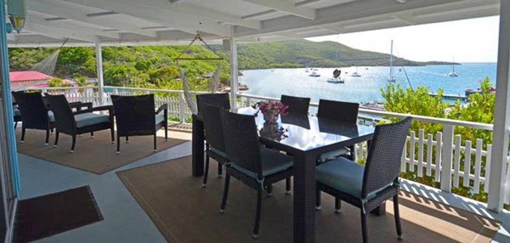 The outdoor dining area on Vista Villa’s covered patio looking out on the blue waters and sail boats on Leverick Bay.