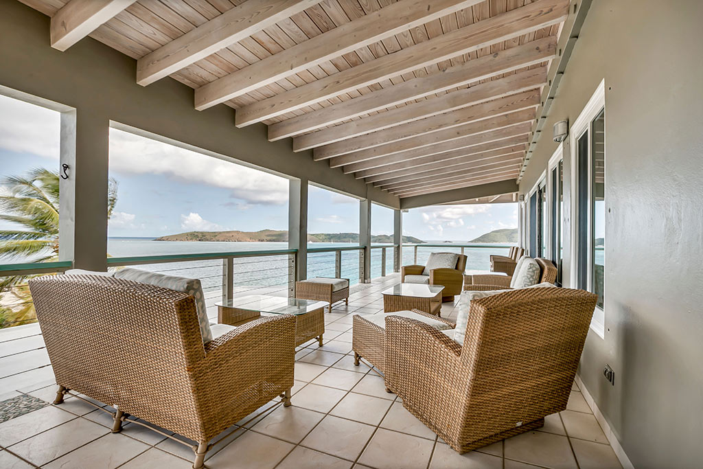 Coconut Grove Villa’s covered tile patio with the blue water of Leverick Bay and surrounding islands in the background.