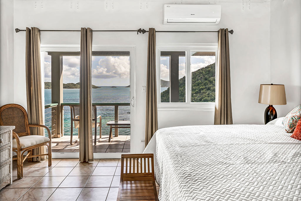 Coconut Grove Villa guest room with a king bed, sitting area and private balcony overlooking beautiful Leverick Bay.