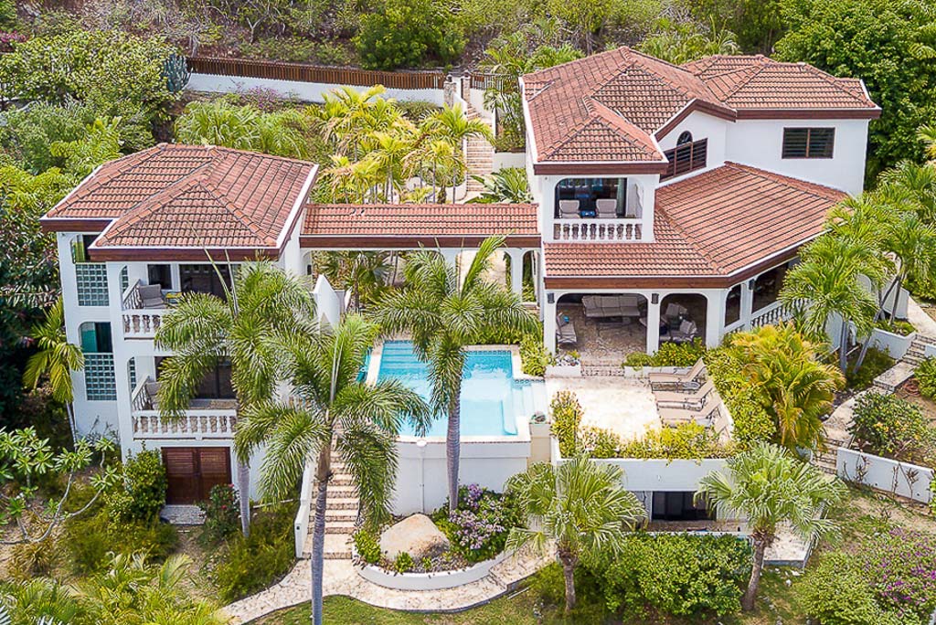 Bellamare luxury villa with a white stone façade and red tile roof on the tropical hillside at Mahoe Bay, Virgin Gorda.