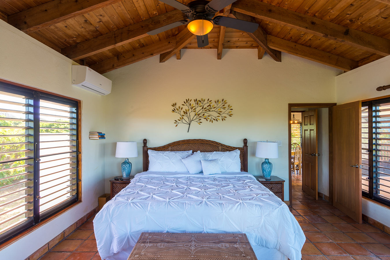 Amani Villa master bedroom with a king bed, natural hues, tile floors and a lofted wood-beam ceiling with a fan light.