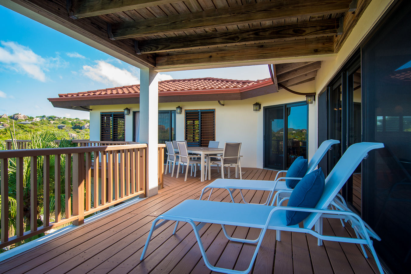 Wrap-around deck with lounging and dining areas on the upper-level of Amani Villa with the island in the background.