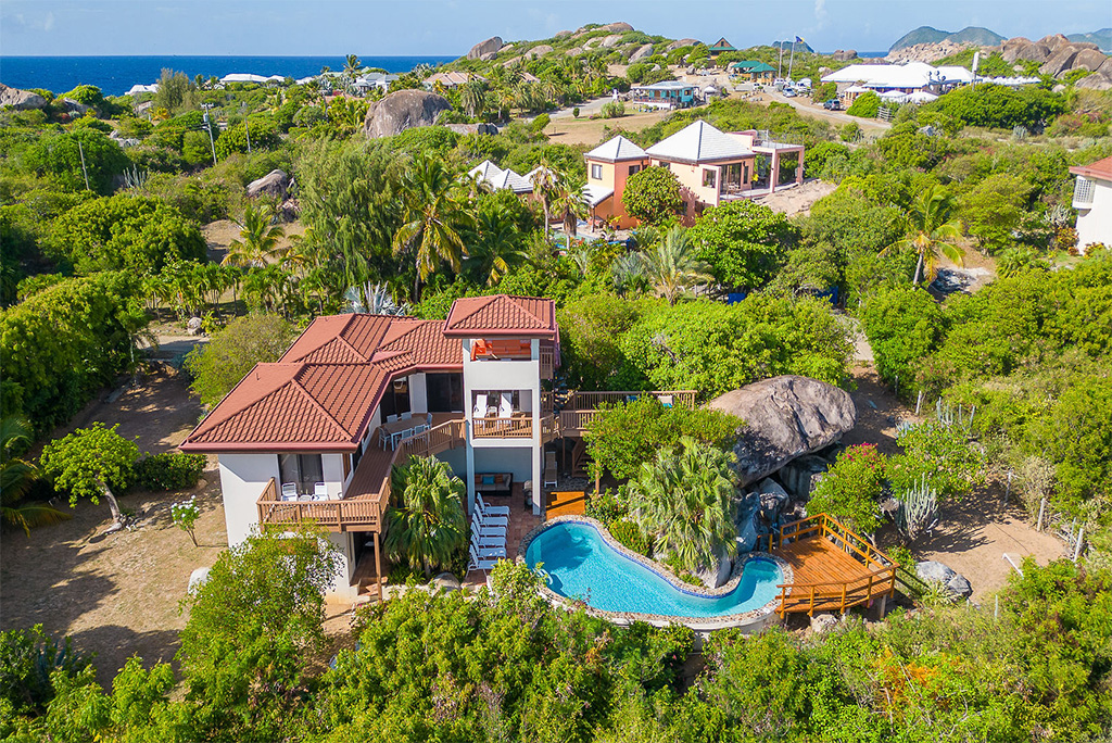 Multi-level Villa Amani with a white stone exterior and red tile roofs in a tropical setting at The Baths in Virgin Gorda.
